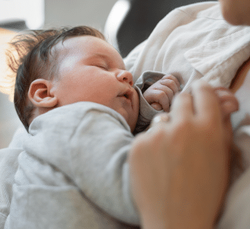 A baby is peacefully sleeping while being held in someone's arms.